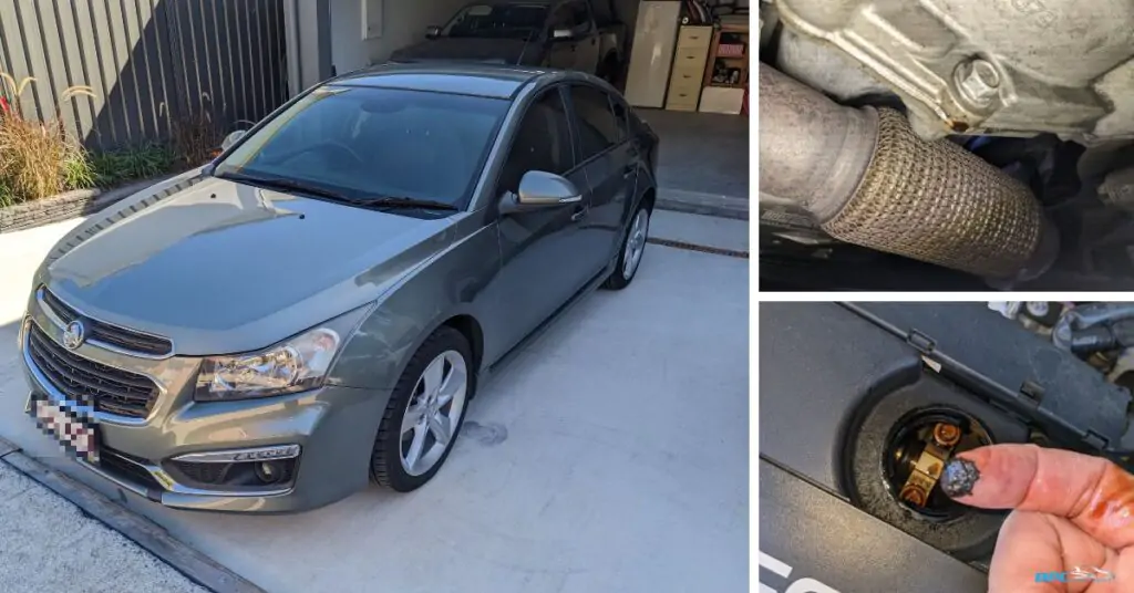 Grey Holden Cruze with the hood open, man's hand reaching into the engine bay, showing engine oil tarnish and oil leak.